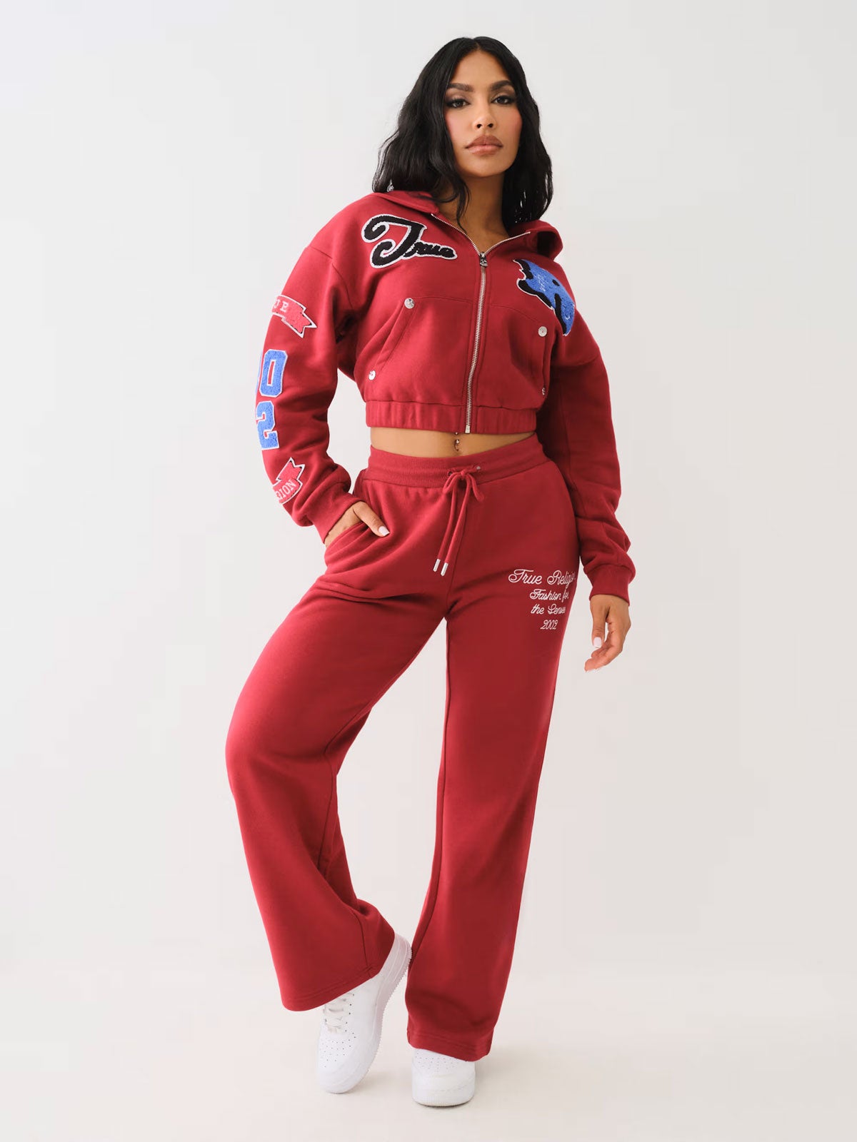 Woman wears a red sweat suit with blue, white, and red detailing on the sweat shirt