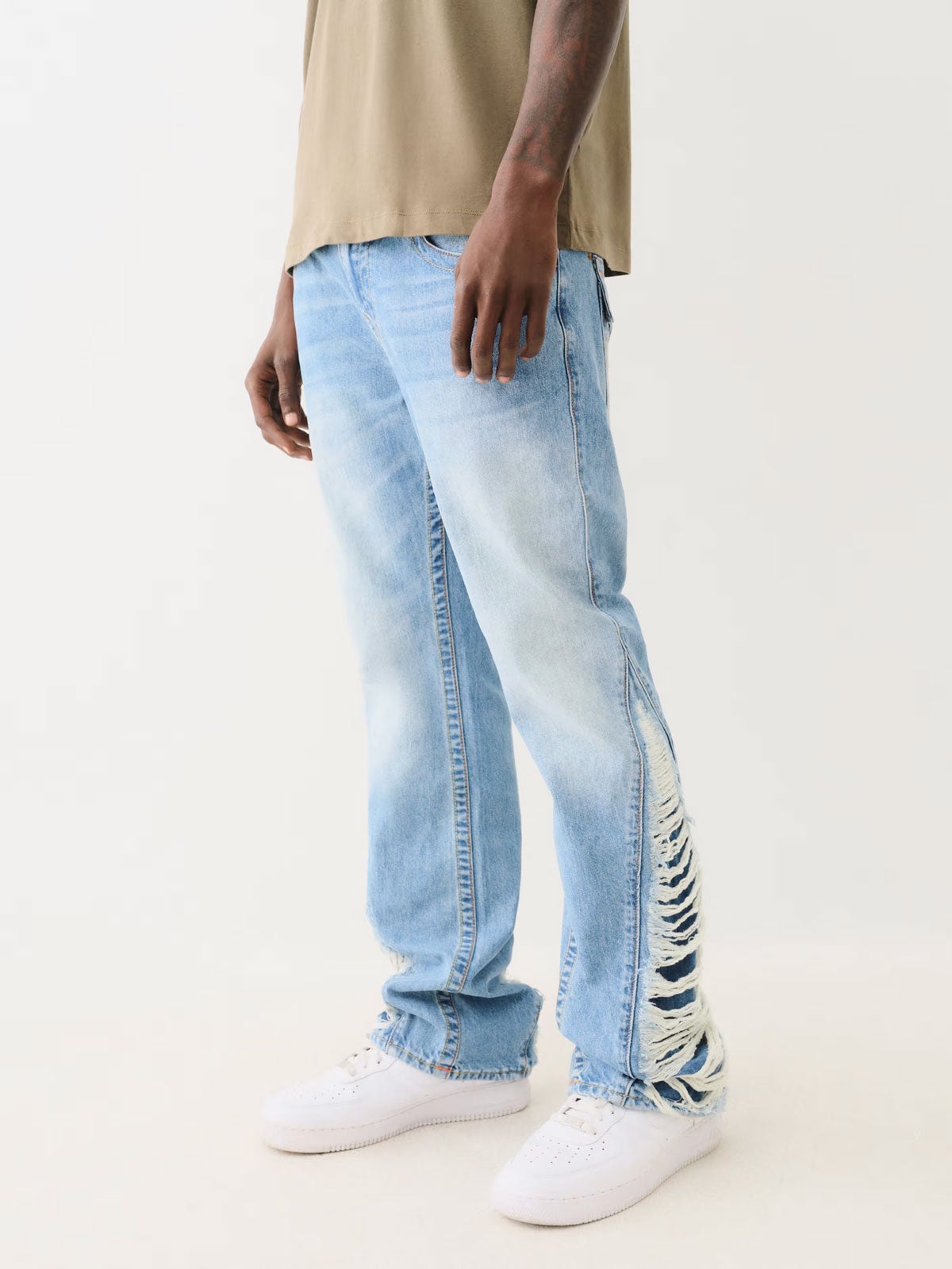 Man wearing True Religion light wash jeans with distressed side hem
