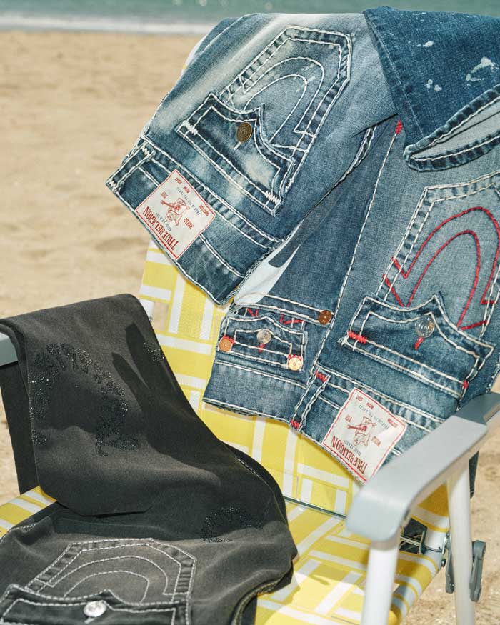True Religion Jeans slung over a yellow beach chair on a beach